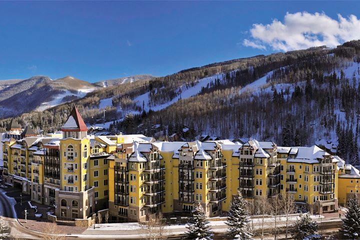 Ritz Carlton Club Vail Exterior of the yellow buildings with red roofs surrounded by snow capped mountains