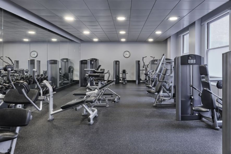 Bright white fitness room with workout equipment 