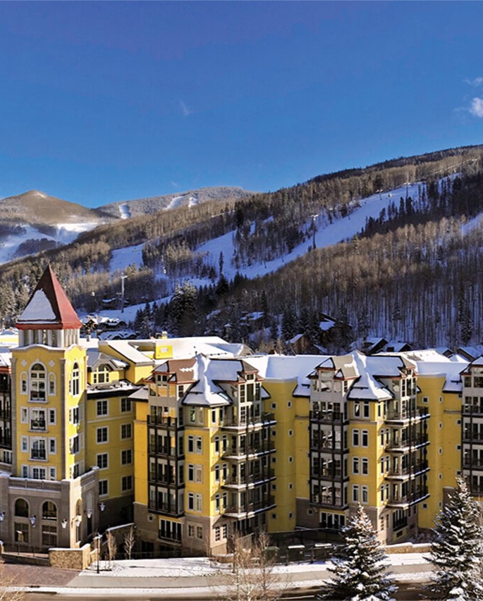 Ritz Carlton Club Vail Exterior of the yellow buildings with red roofs surrounded by snow capped mountains