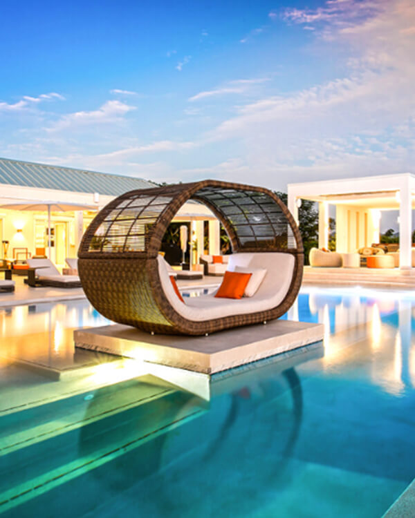 Modern oval cabana in the middle of an elegantly lit pool at sunset.