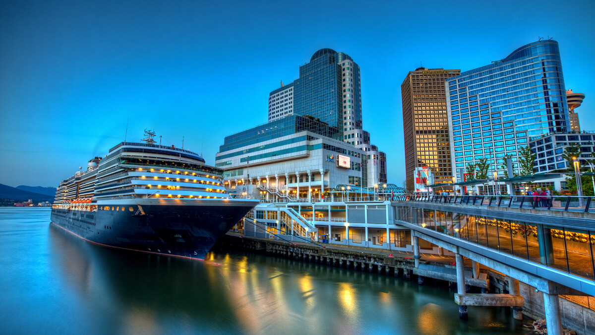 Cruise ship in port at sunset with sparkling lights on the water.