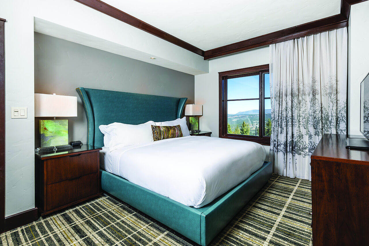 Bedroom with a king-sized blue leather headboard, white linens, and neutral colors.