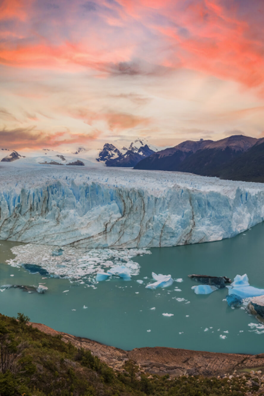 Glaciers of Alaska with colorful sky above and green blue water