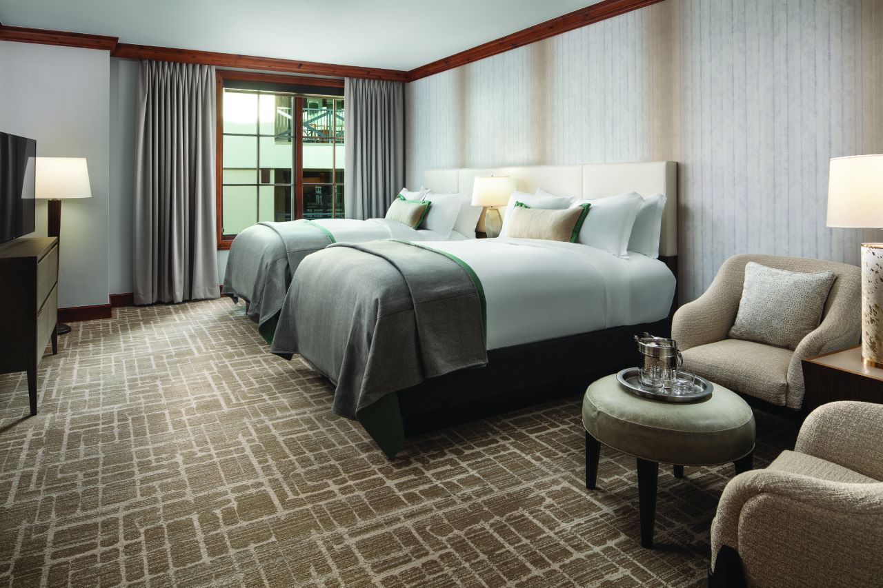 Resort bedroom with two beds with white linens and cream headboards.