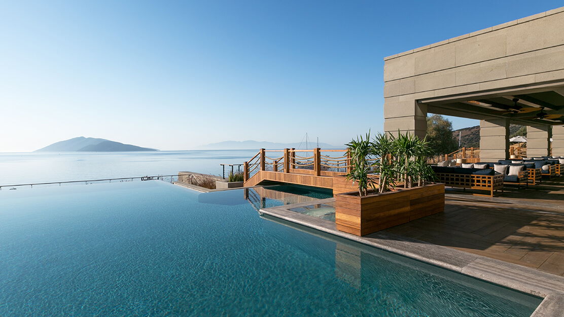 Resort with infinity pool and wood accents with a view of the water and mountain in the background