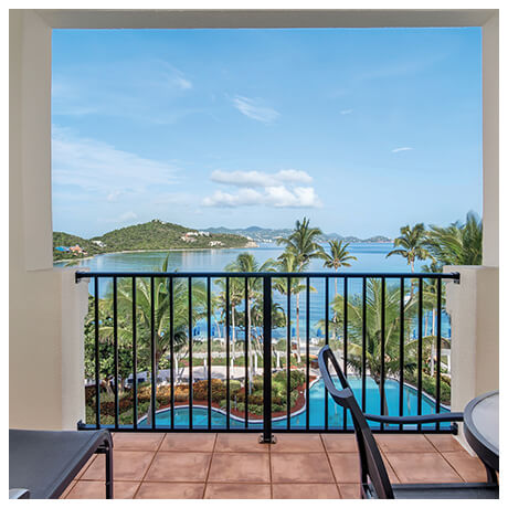 Looking out of a resort balcony to the blue water ocean view.