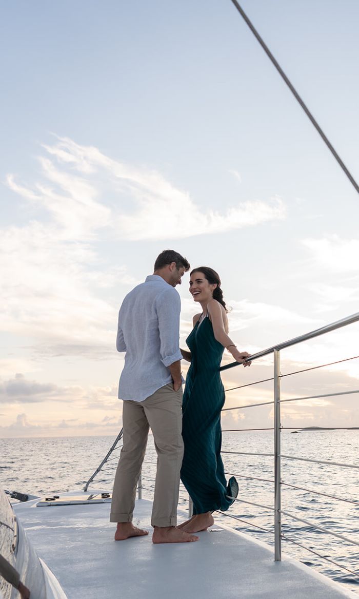 Barefoot couple dressed for the evening standing by the rail on a catamaran