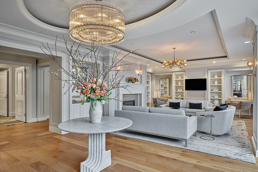 Exclusive members lounge at The Ritz-Carlton Club, San Francisco, with light gray furniture, gold accents, chandeliers, and light wood floors